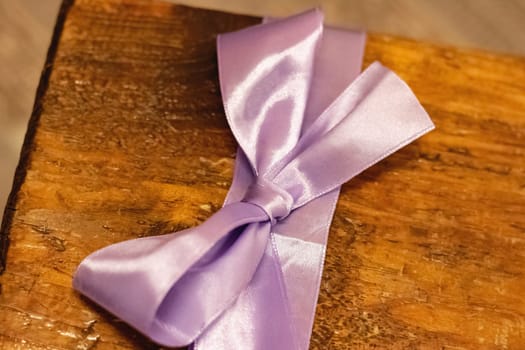 Pink bow on a wooden box with a gift close up