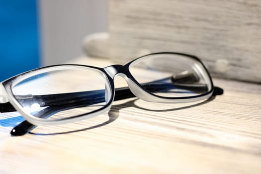 Black glasses for vision on a wooden table close up