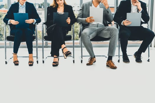 Businesswomen and businessmen holding resume CV folder while waiting on chairs in office for job interview. Corporate business and human resources concept. uds