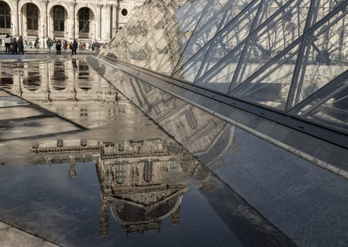 France, Paris - Jan 03, 2024 - View of The historical palace building in water reflection effect by after raining at the front of Louvre pyramid in the Louvre museum in Paris. is one of the world's largest museums in Paris, Space for text, Selective focus.