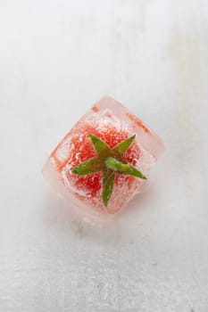 Photographic documentation of some small tomatoes inside an ice cube 