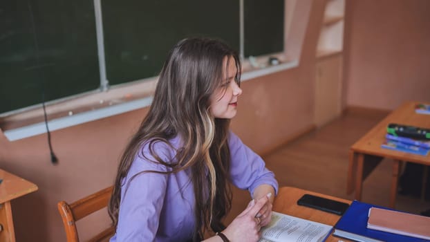 A young female student leads the class in the role of teacher