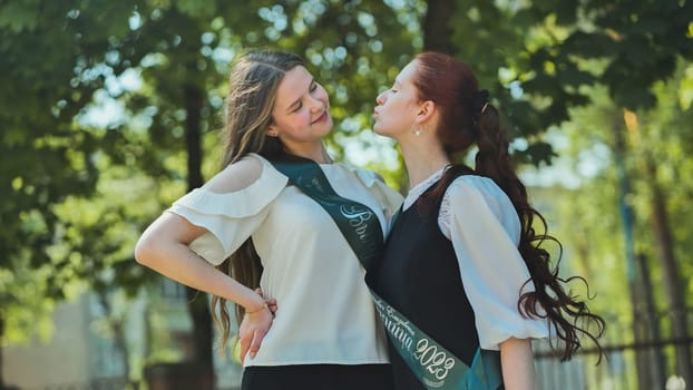 Two high school senior girls playfully sort of kissing