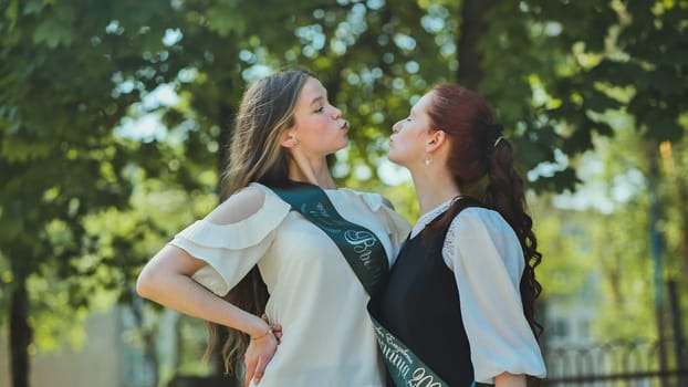 Two high school senior girls playfully sort of kissing