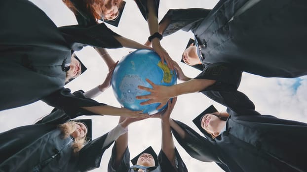 Graduating students twirl a geographic globe of the world in their hands