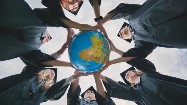 Graduating students twirl a geographic globe of the world in their hands