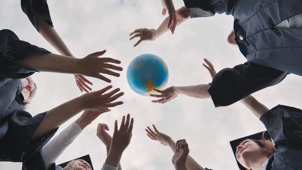 College alumni students toss a globe of the world into the sky