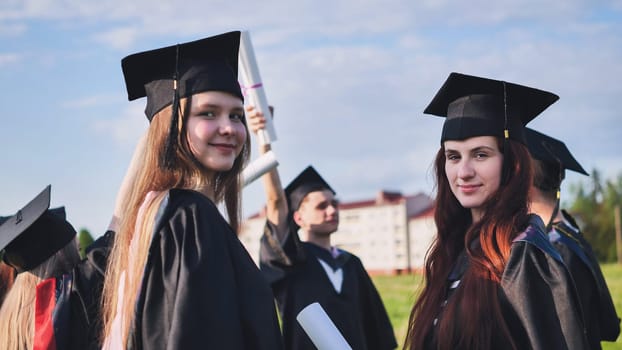 Portraits of graduating girls in black robes on the street