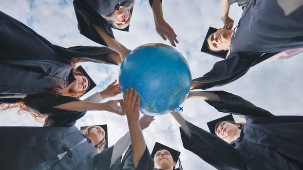 Graduating students twirl a geographic globe of the world in their hands