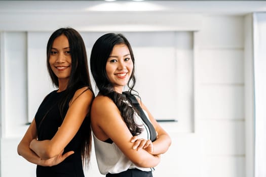 Two young Asian businesswomen sitting in office. Business friends and community concept. uds