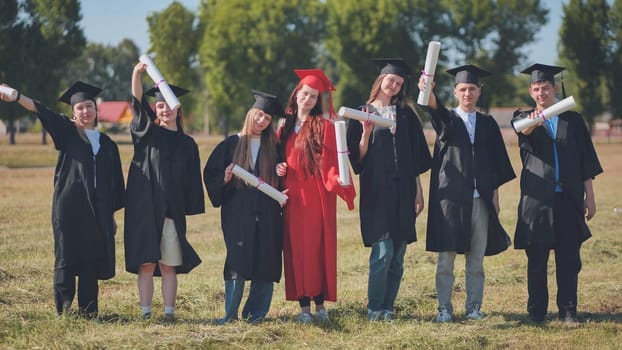 Young graduates pose with diplomas in hand on the street