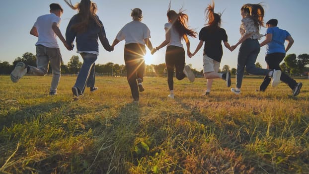 Children running on meadow at sunset