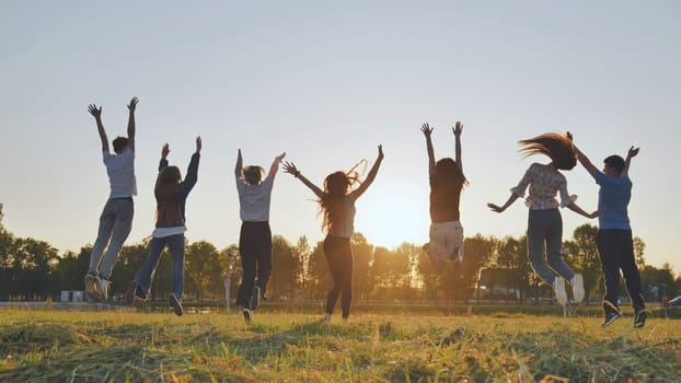 Merry friends jumping around at sunset