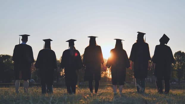 Silhouettes of college graduates standing in a meadow