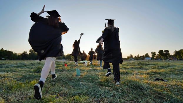 Cheerful graduates students run after school at sunset