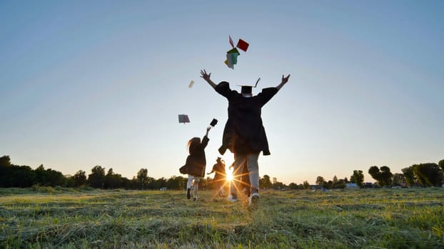 Cheerful graduates students run after school at sunset