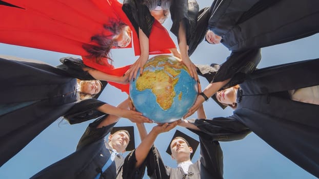 College graduates stand in a circle and hold a geographical globe of the world