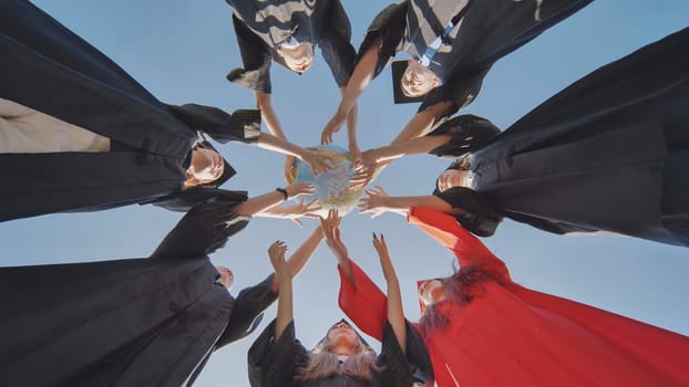 College alumni students toss a globe of the world into the sky