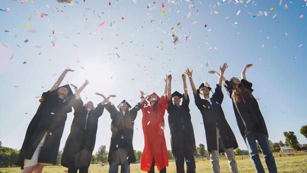 Happy college graduates throw colorful confetti against the rays of sunshine
