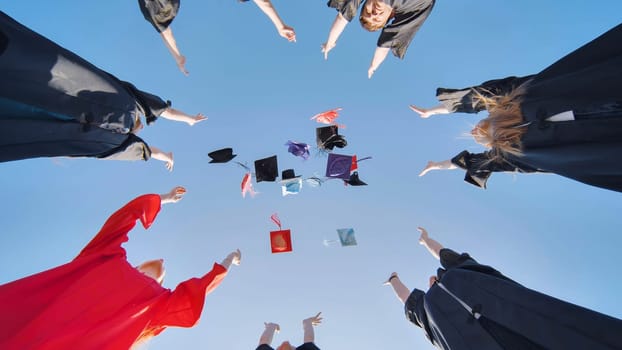 Graduates tossing multicolored hats against a blue sky