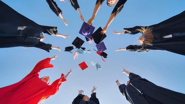 Graduates tossing multicolored hats against a blue sky