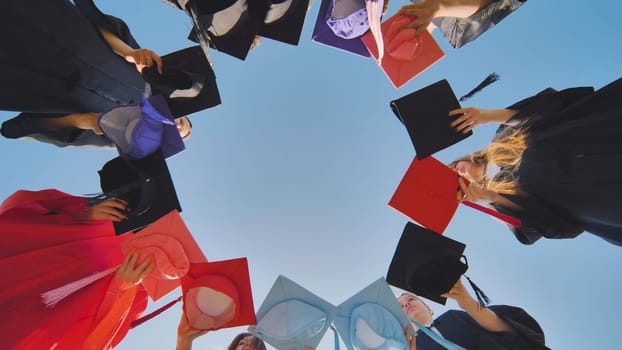 Graduates tossing multicolored hats against a blue sky