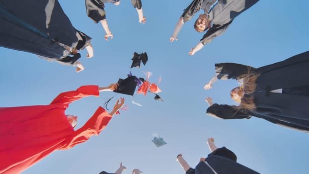 Graduates tossing multicolored hats against a blue sky