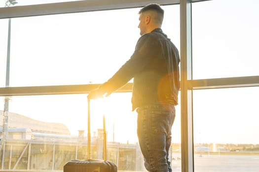 A young man waiting to board at the airport during sunset