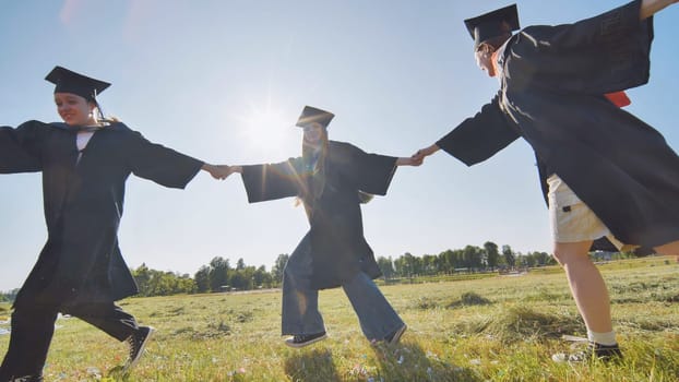 College graduates holding hands run in a round dance