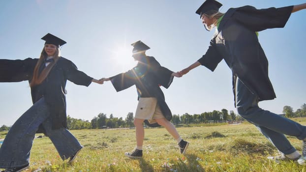 College graduates holding hands run in a round dance