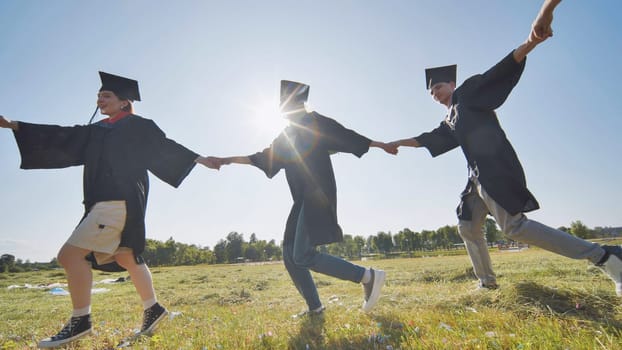 College graduates holding hands run in a round dance