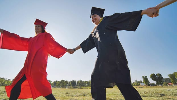 College graduates holding hands run in a round dance