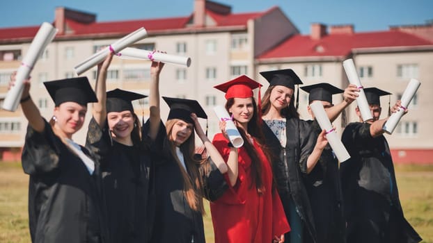 Students graduate holding their diplomas at the top