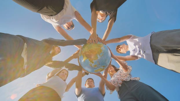 Friends holding a geographical globe in their hands. The concept of keeping the world safe