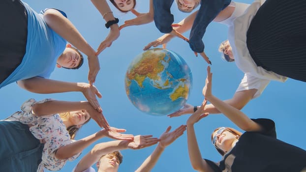 Young friends surround the globe of the world with their palms. The concept of preserving world peace