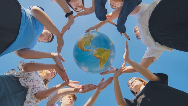 Young friends surround the globe of the world with their palms. The concept of preserving world peace