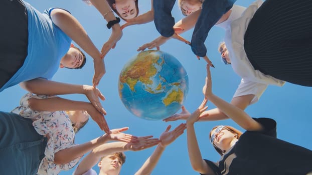 Young friends surround the globe of the world with their palms. The concept of preserving world peace