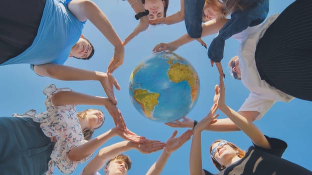 Young friends surround the globe of the world with their palms. The concept of preserving world peace