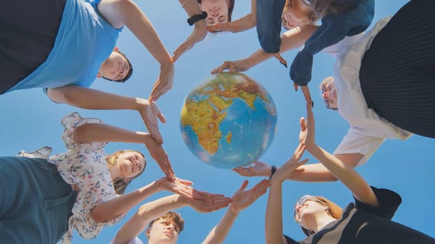 Young friends surround the globe of the world with their palms. The concept of preserving world peace