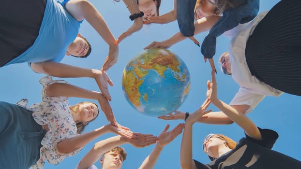 Young friends surround the globe of the world with their palms. The concept of preserving world peace