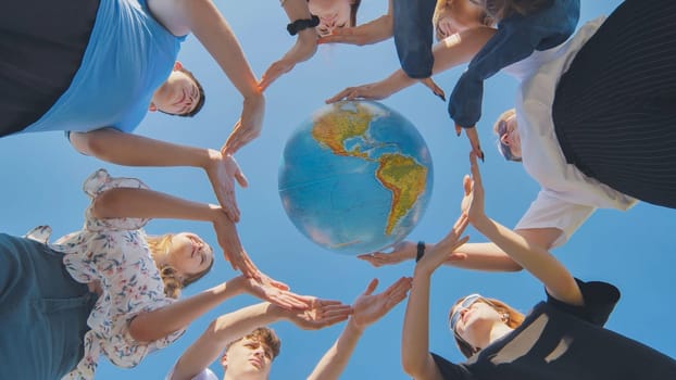 Young friends surround the globe of the world with their palms. The concept of preserving world peace