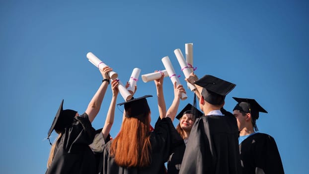 College graduates with caps tie their diplomas together