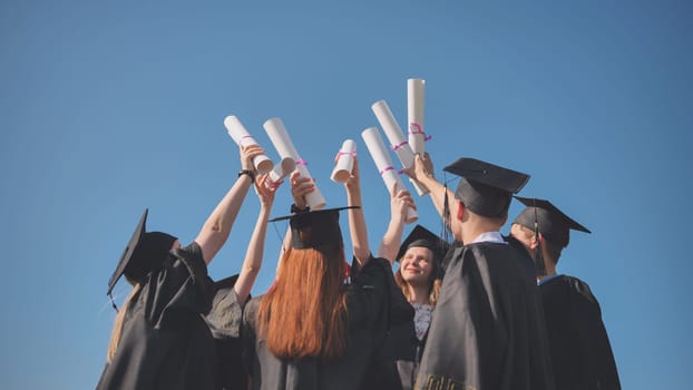 College graduates with caps tie their diplomas together