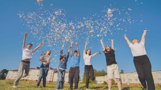 Friends toss colorful paper confetti from their hands