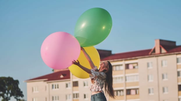 A girl happily poses with large with colorful balloons in the city