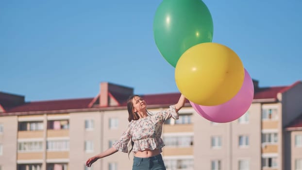 A girl happily poses with large with colorful balloons in the city
