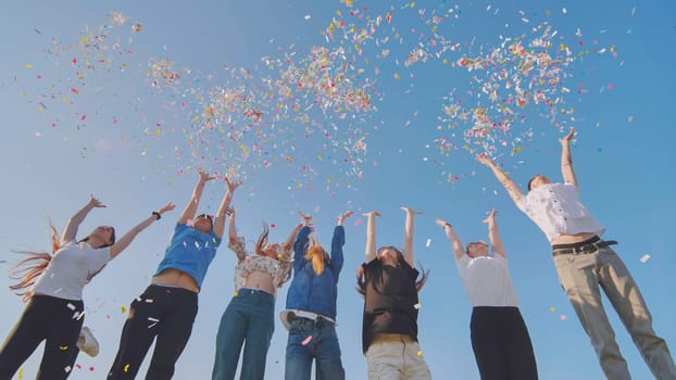 Friends toss colorful paper confetti from their hands