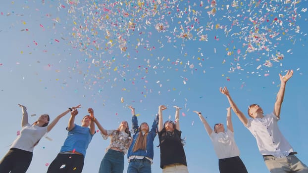 Friends toss colorful paper confetti from their hands