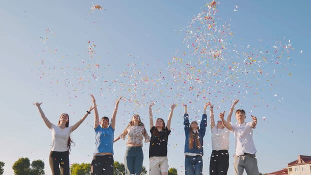 Friends toss colorful paper confetti from their hands