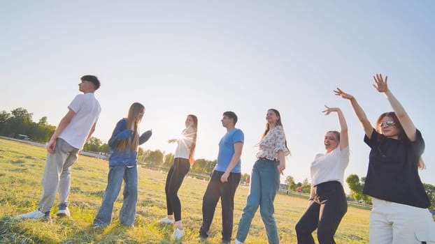 Funny jolly friends dancing in the city meadow in the evening